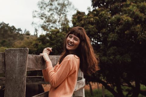 微笑的女人站着，拿着木栅栏