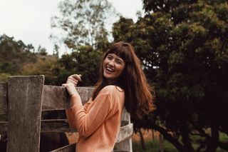 微笑的女人站着，拿着木栅栏