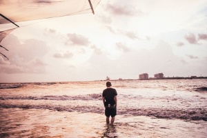 一个年轻的白人男子在海滩上的海水中涉水