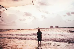 一个年轻的白人男子在海滩上的海水中涉水