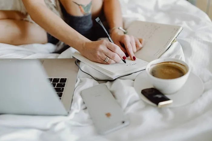 在床上享用早餐咖啡和巧克力时，一位女士在笔记本电脑上工作