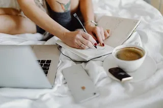 在床上享用早餐咖啡和巧克力时，一位女士在笔记本电脑上工作