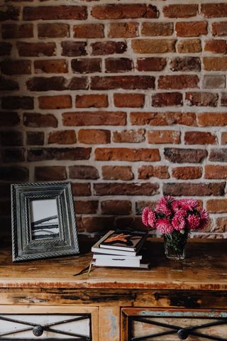 相框、书籍和粉红色的花朵放在木制马桶上的花瓶里