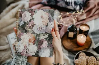 躺在床上的笔记本上写东西，里面有咖啡、蜡烛和姜饼