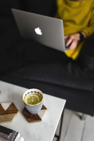 坐在沙发上用笔记本电脑工作的年轻女子