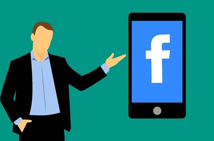 站在运行facebook社交媒体应用的移动设备旁的男子。