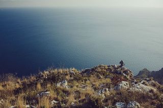 阴天，站在悬崖附近观看水体的人