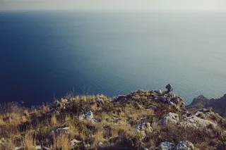 阴天，站在悬崖附近观看水体的人