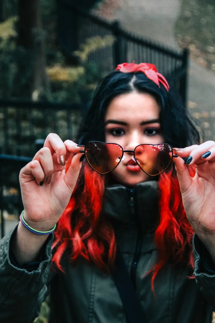 手持心形镜框太阳镜的女子