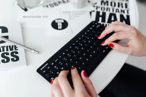 女性用手在远程无线电脑键盘上打字