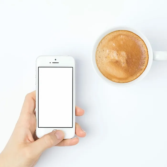 白色陶瓷杯旁的银色iPhone 5s 白色陶瓷杯旁的银色iPhone 5s