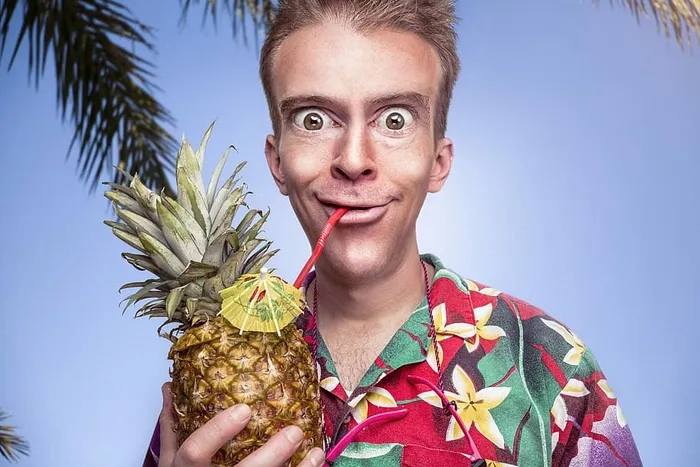 身穿红、黄、绿flora纽扣衬衫的男子在蓝天下举着菠萝