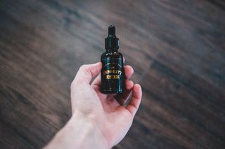 拿着黑色和金色标签滴管瓶的人