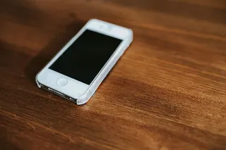 桌上放着笔记本电脑、智能手机、杂志和咖啡