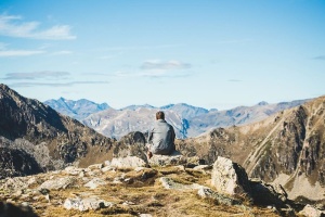 一位旅行者坐在悬崖边观看群山的后视图