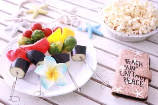 爆米花附近圆形陶瓷板上的蔬菜串和棕色皮革在白色木质表面翻转手机壳