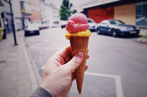 拿着粉红色和黄色冰淇淋和甜筒的人