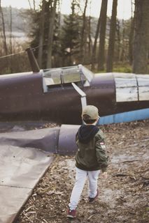 棕色飞机旁穿着绿色夹克的男孩