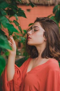 身穿红衬衫的女人抚摸绿叶树