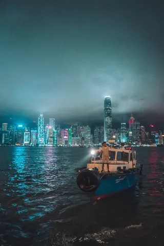 夜间站在建筑物附近渔船上的人