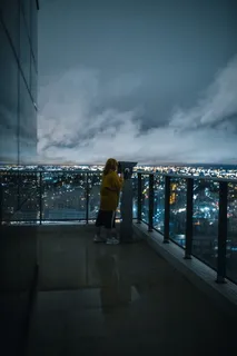 穿着黄色毛衣的女人看着灯火通明的城市 穿着黄色毛衣的女人看着灯火通明的城市