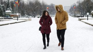 穿着棕色派克大衣的男人走在穿着栗色外套的女人旁边