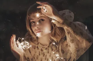 身着白色花朵连衣裙的女子举着打开的吊灯的照片