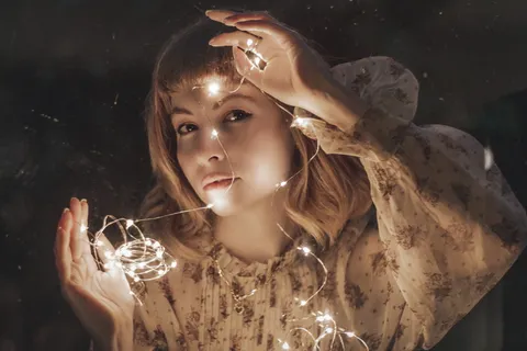 身着白色花朵连衣裙的女子举着打开的吊灯的照片 身着白色花朵连衣裙的女子举着打开的吊灯的照片