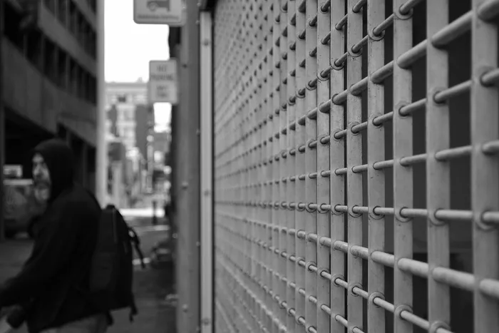 白色窗框前穿着连帽衫的男子的灰度照片