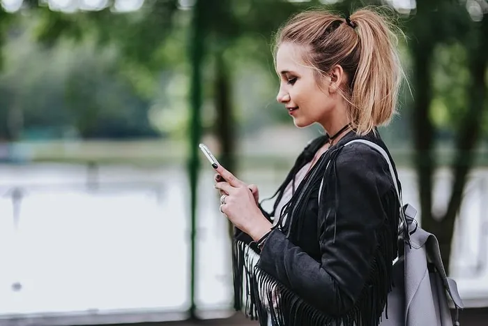 穿着黑色夹克和绿色扶手撕破牛仔裤的金发女人