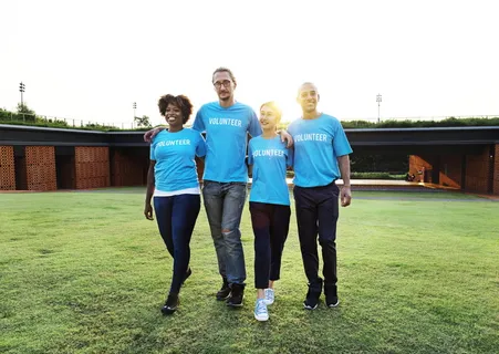 四个人穿着蓝色圆领衬衫站在草坪上