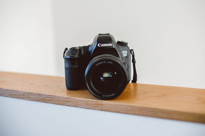 棕色木板上的黑色佳能 DSLR 相机