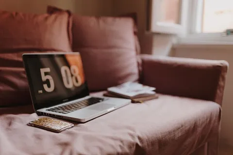 在粉色沙发上放着笔记本电脑的工作场所