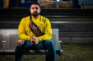 身穿黄色长袖衬衫的男子坐在灰色长凳上