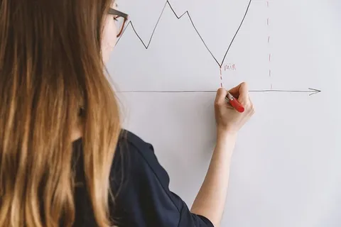 一名年轻女子在教室的活动板上写字的后视图