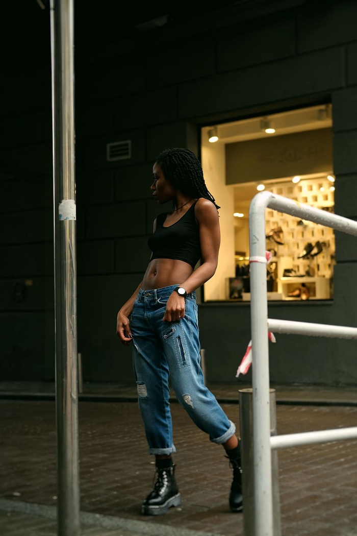 一名身穿黑色短上衣的女子举着牛仔裤站在商店门口的照片