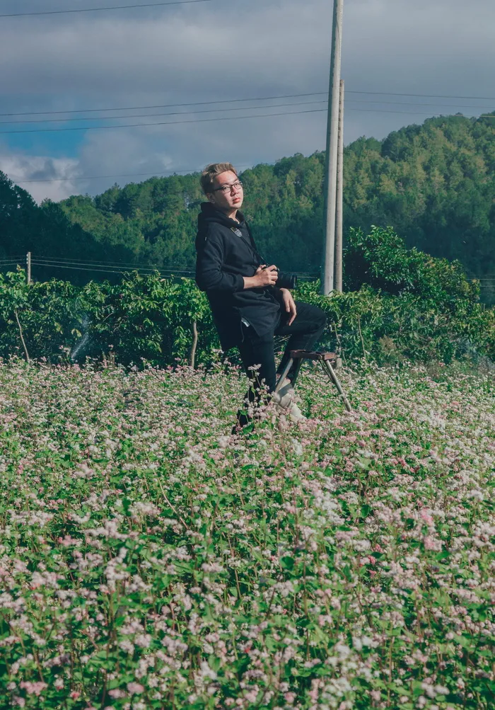 白天，一名男子在绿色灌木丛上手持黑色单反相机