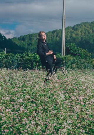 白天，一名男子在绿色灌木丛上手持黑色单反相机