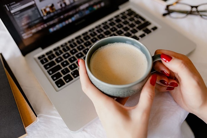 一位女士在一张桌子旁工作，桌上有一台笔记本电脑和一杯咖啡