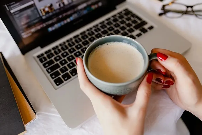 一位女士在一张桌子旁工作，桌上有一台笔记本电脑和一杯咖啡