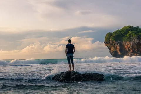 日出摄影时,一名男子站在海边的石头上 日出摄影时,一名男子站在海边的石头上