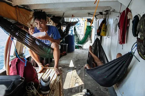 男人边吃边坐在吊床上