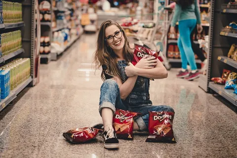 一位面带微笑的女士坐在购物通道*，手里拿着多里托薯片