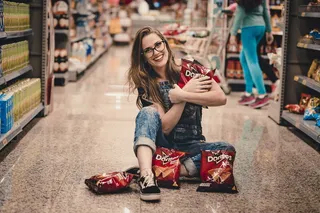 一位面带微笑的女士坐在购物通道*，手里拿着多里托薯片