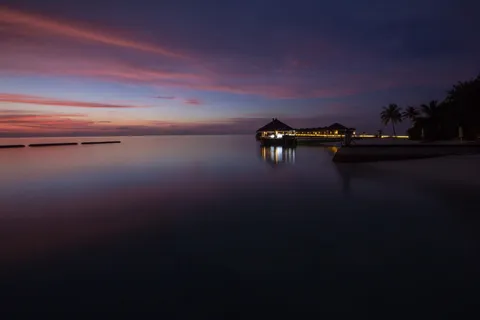 在粉红色的天空夕阳中,海滩上的露台被照亮 在粉红色的天空夕阳中,海滩上的露台被照亮