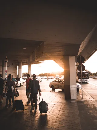 沿着机场入口拉行李袋的男人