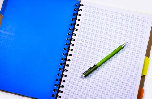 室内白色直纹纸上的绿色和银色推笔 室内白色直纹纸上的绿色和银色推笔