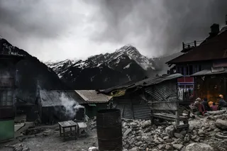 灰色木制工作台和波纹板棚附近的圆柱形黑色金属容器