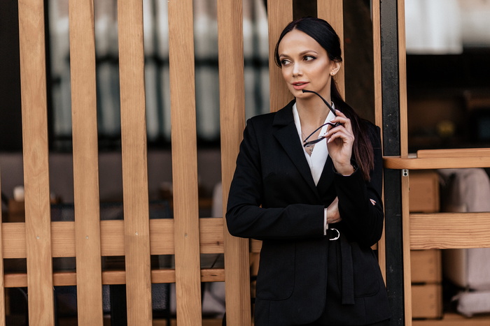 一位身穿黑色西装夹克的女士靠在墙上