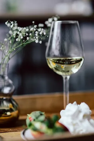 木托盘上的草莓、奶油和白葡萄酒